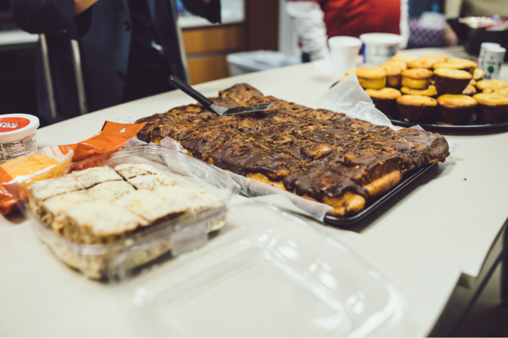 Assortment of baked goods on a table, including cinnamon rolls, muffins, and dessert bars.