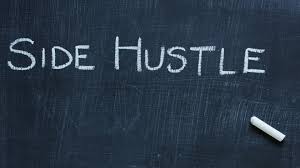 The words “Side Hustle” written in white chalk on a blackboard with a piece of chalk resting nearby.