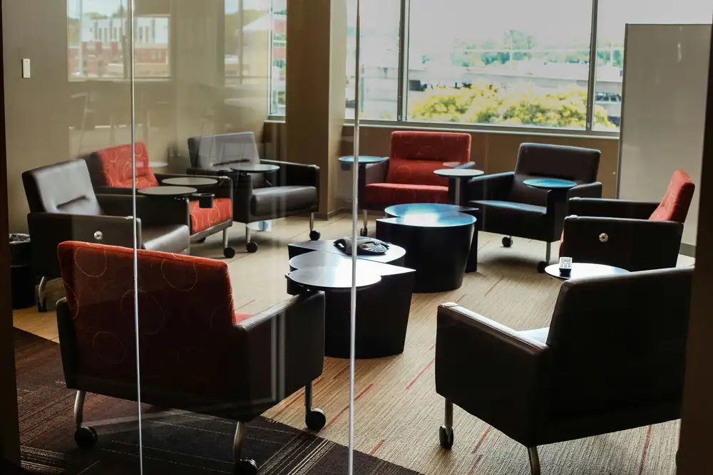 Modern meeting room with six armchairs, black coffee tables, and large windows.