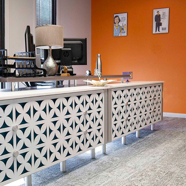 Office space at Modern Work Suites & Studio featuring a white decorative cabinet with star patterns, an orange wall, and stylish decor.